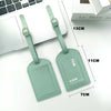 Two mint green PU leather luggage tags with ID card holders shown next to a laptop.