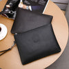 A black elegant PU leather men's clutch wallet resting on a wooden table next to a magazine.