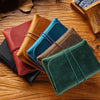 A collection of five minimalist full-grain leather passport holders and card wallets in various earthy tones are arranged on 