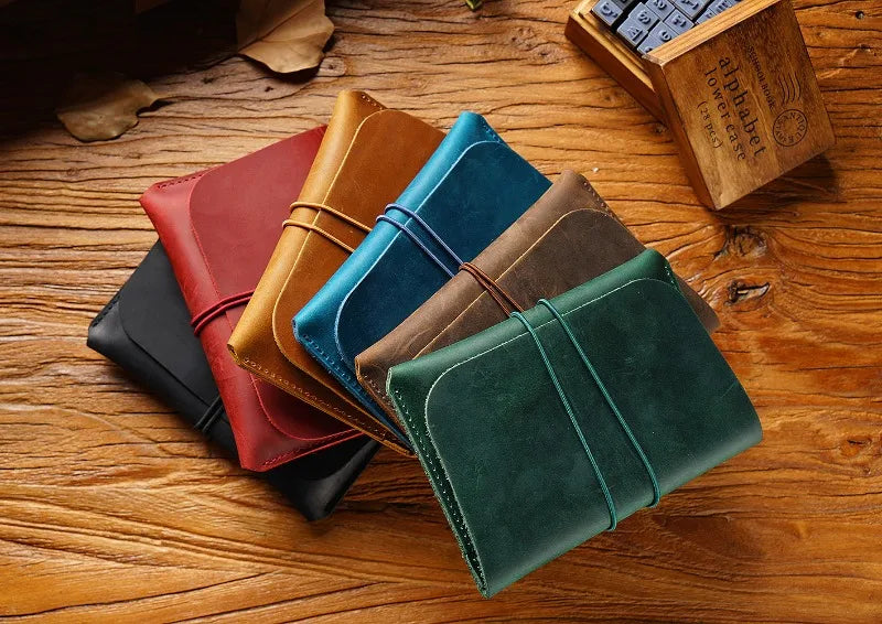 A collection of five minimalist full-grain leather passport holders and card wallets in various earthy tones are arranged on 