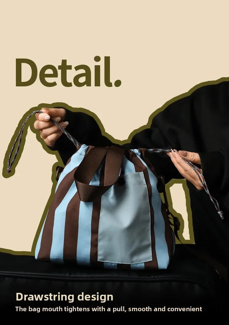 A hand holds a striped insulated lunch bag, demonstrating its drawstring design.