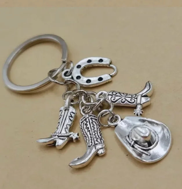 Silver keychain set featuring a cowboy boot, hat, and horseshoe charms.