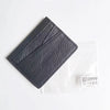 Porte-cartes en cuir véritable noir texturé, vue en diagonale sur fond blanc.