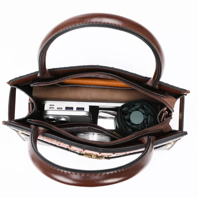 A brown PU leather shoulder handbag with a leather strap and a dark green lens attached.