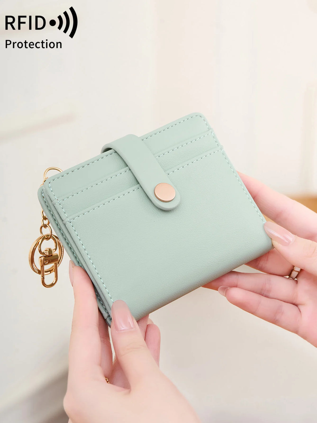A light mint green minimalist RFID blocking wallet is being held by a person, showing its design and hardware.