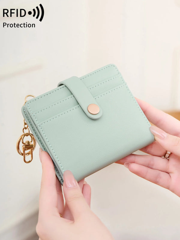 A light mint green minimalist RFID blocking wallet is being held by a person, showing its design and hardware.