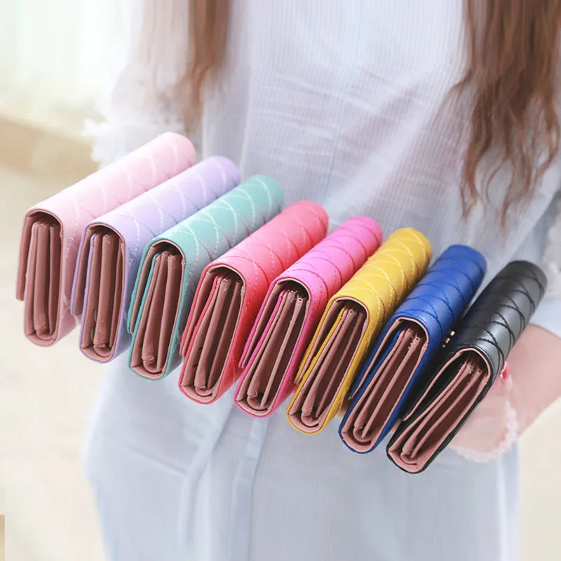 A collection of elegant diamond quilted long wallets in various pastel colors are displayed by a person.
