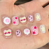 A set of cute cartoon press-on nails featuring various designs including smiling cats and flowers on a hand.