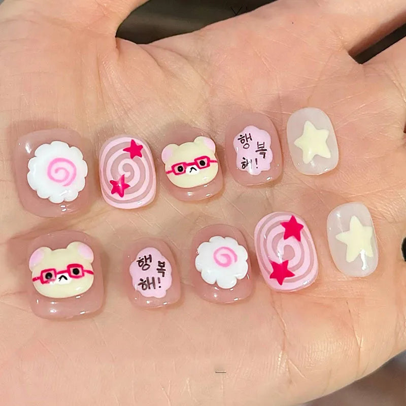 A set of cute cartoon press-on nails featuring various designs including smiling cats and flowers on a hand.