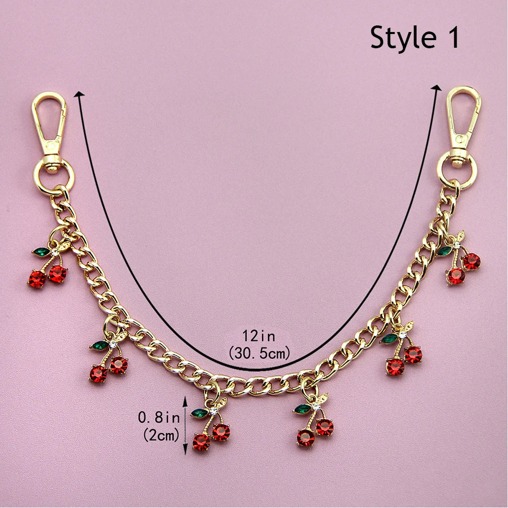 Accesorio de cadena dorada con corazones de esmalte y flores de cerezo, mostrado contra un fondo rosa.