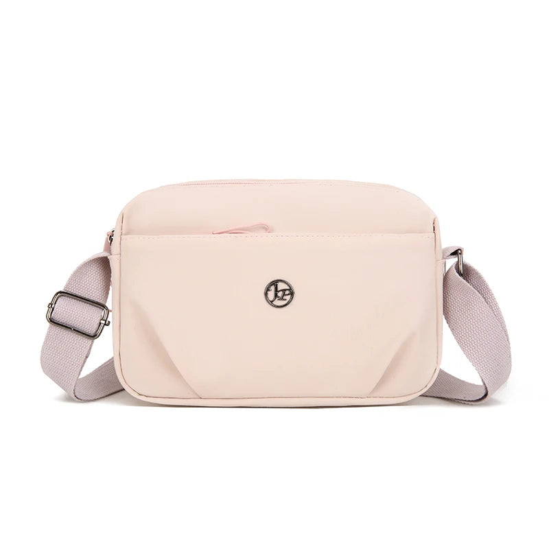 Bolso cruz impermeable de nylon rosa claro con solapa y correa ajustable.
