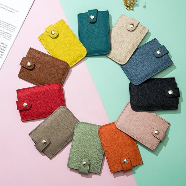 A collection of genuine leather slim card holders in various shades of green, yellow, brown, and pink arranged on a light bac
