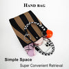 A black and tan striped knitted contrast tote handbag with a silver ring and a black and white patterned strap.