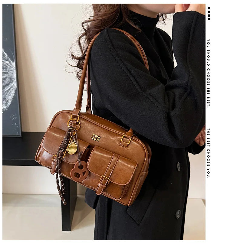 Una mujer sostiene un bolso de cuero PU marrón retro contra un suéter de cuello alto negro.