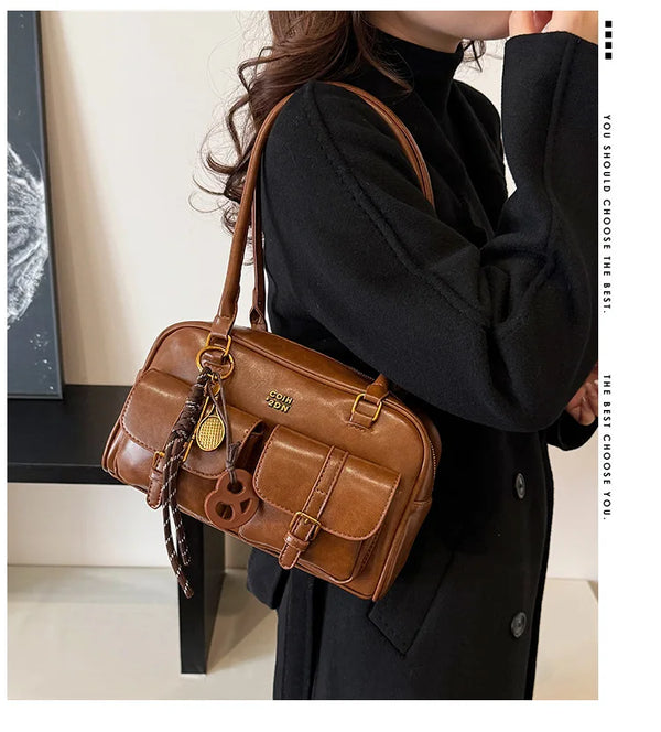 A woman holds a brown retro PU leather shoulder bag against a black turtleneck sweater.