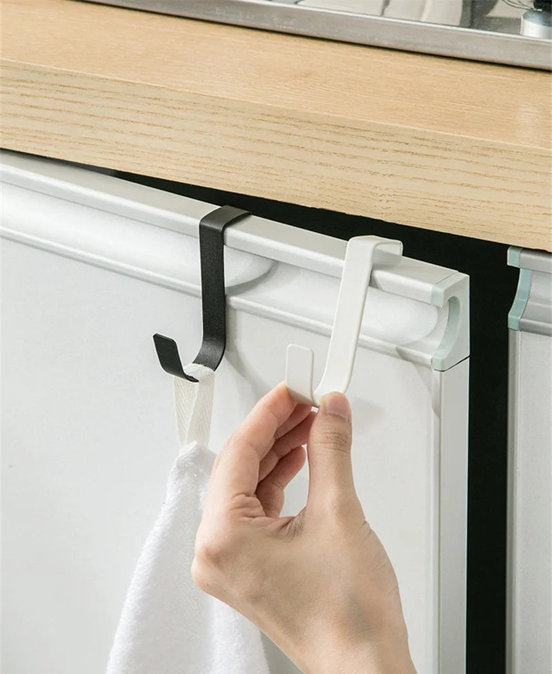A hand is installing a heavy duty multi-purpose hook rack onto a white cabinet door using a white and black mounting system.