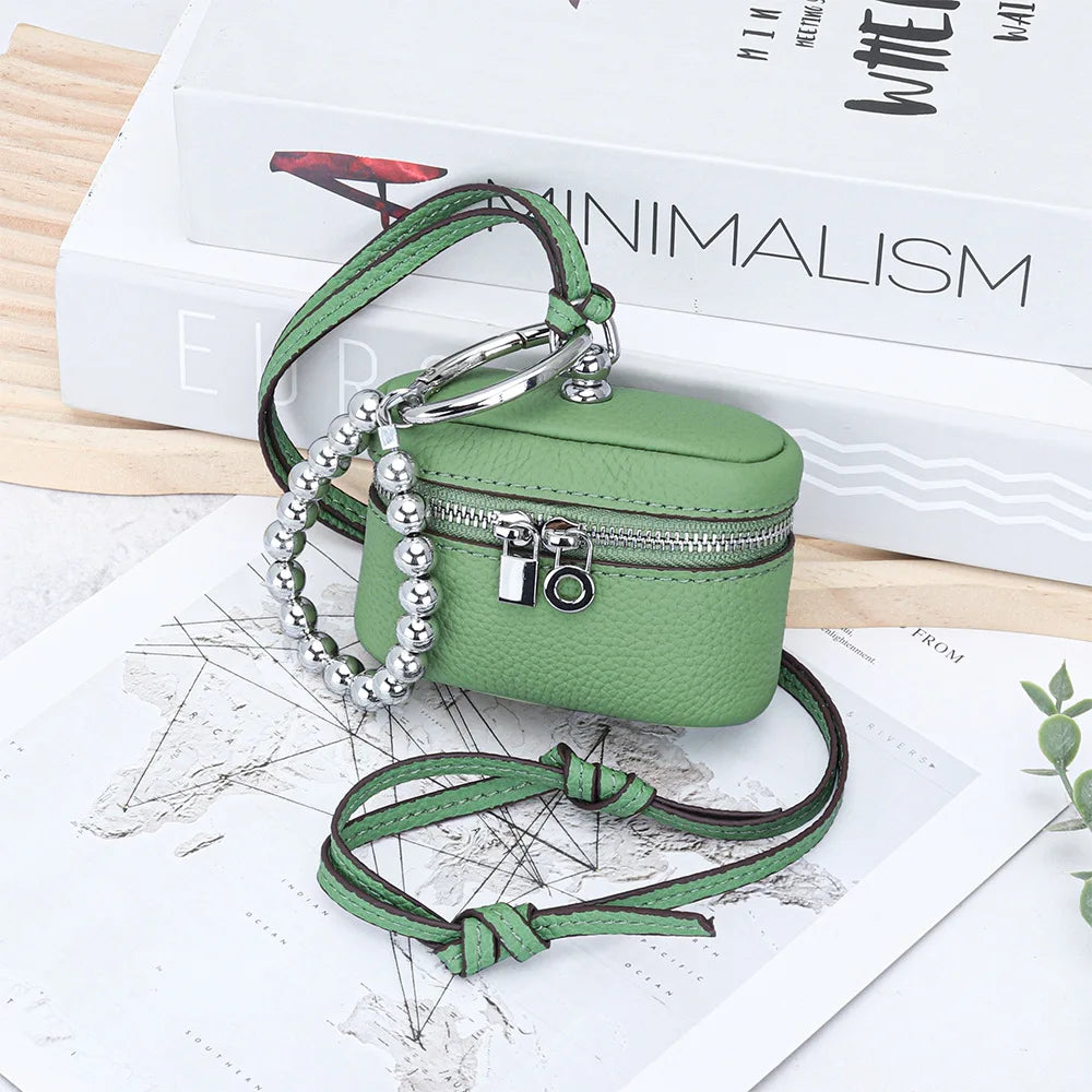 A handcrafted leather coin purse in olive green with a silver chain and lanyard resting on a map.
