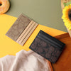 A stack of three elegant PU leather card holders in gold, beige, and black resting on a yellow surface.