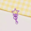 A purple metal keychain clasp set shaped like a star and a loop, resting on a yellow checkered cloth.