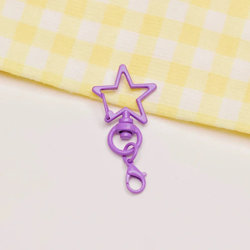 A purple metal keychain clasp set shaped like a star and a loop, resting on a yellow checkered cloth.