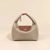 A beige waterproof nylon crossbody bag with dual leather straps resting on a light background.