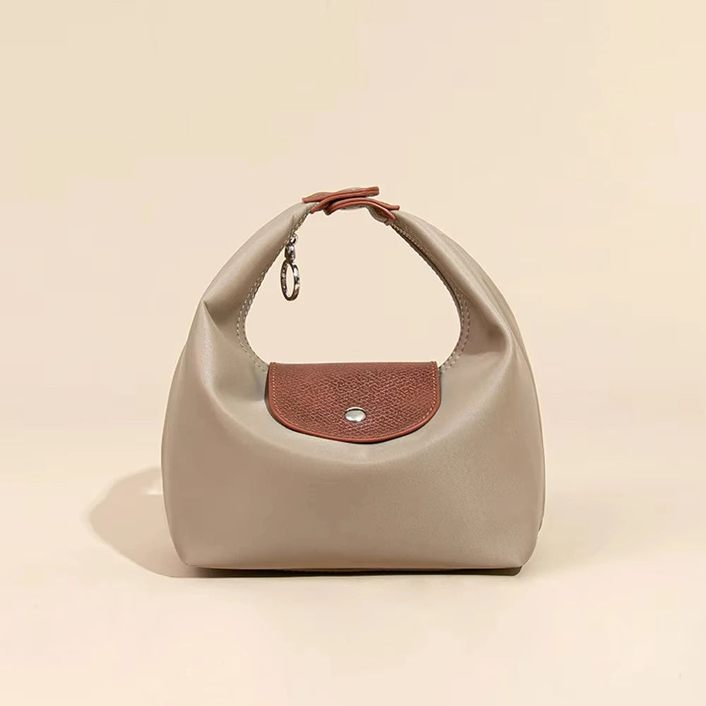 A beige waterproof nylon crossbody bag with dual leather straps resting on a light background.