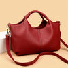 A deep red luxury soft leather women's tote bag with a handle and strap is shown against a light background.