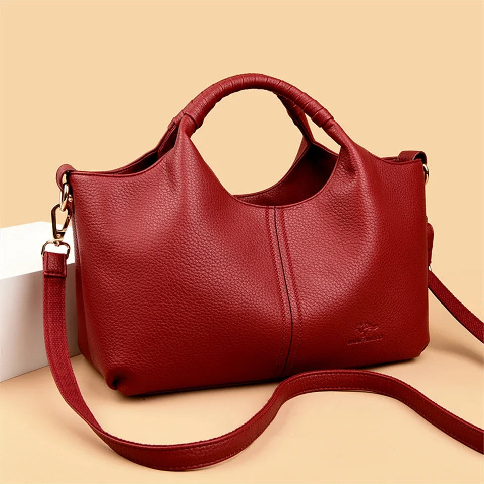 A deep red luxury soft leather women's tote bag with a handle and strap is shown against a light background.