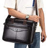 A person holds a black genuine cowhide leather briefcase bag against a white shirt.