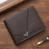 A dark brown men's slim leather bi-fold wallet resting on a wooden surface next to a gold pen.