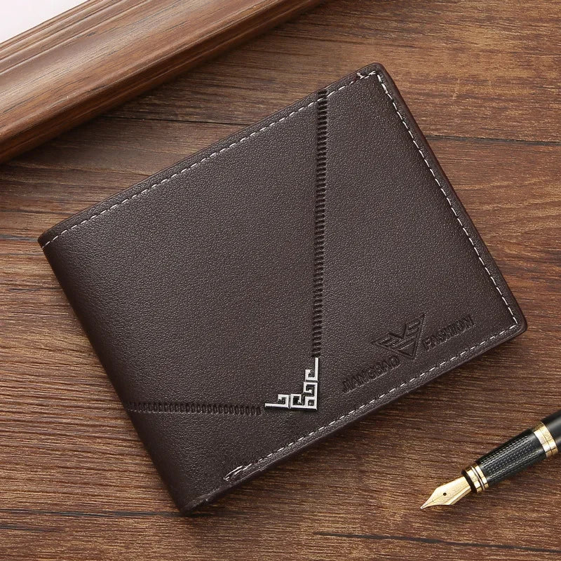A dark brown men's slim leather bi-fold wallet resting on a wooden surface next to a gold pen.