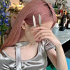 A woman with pink hair is holding her hand to her eyes, showing a set of silver metal star hairpins.