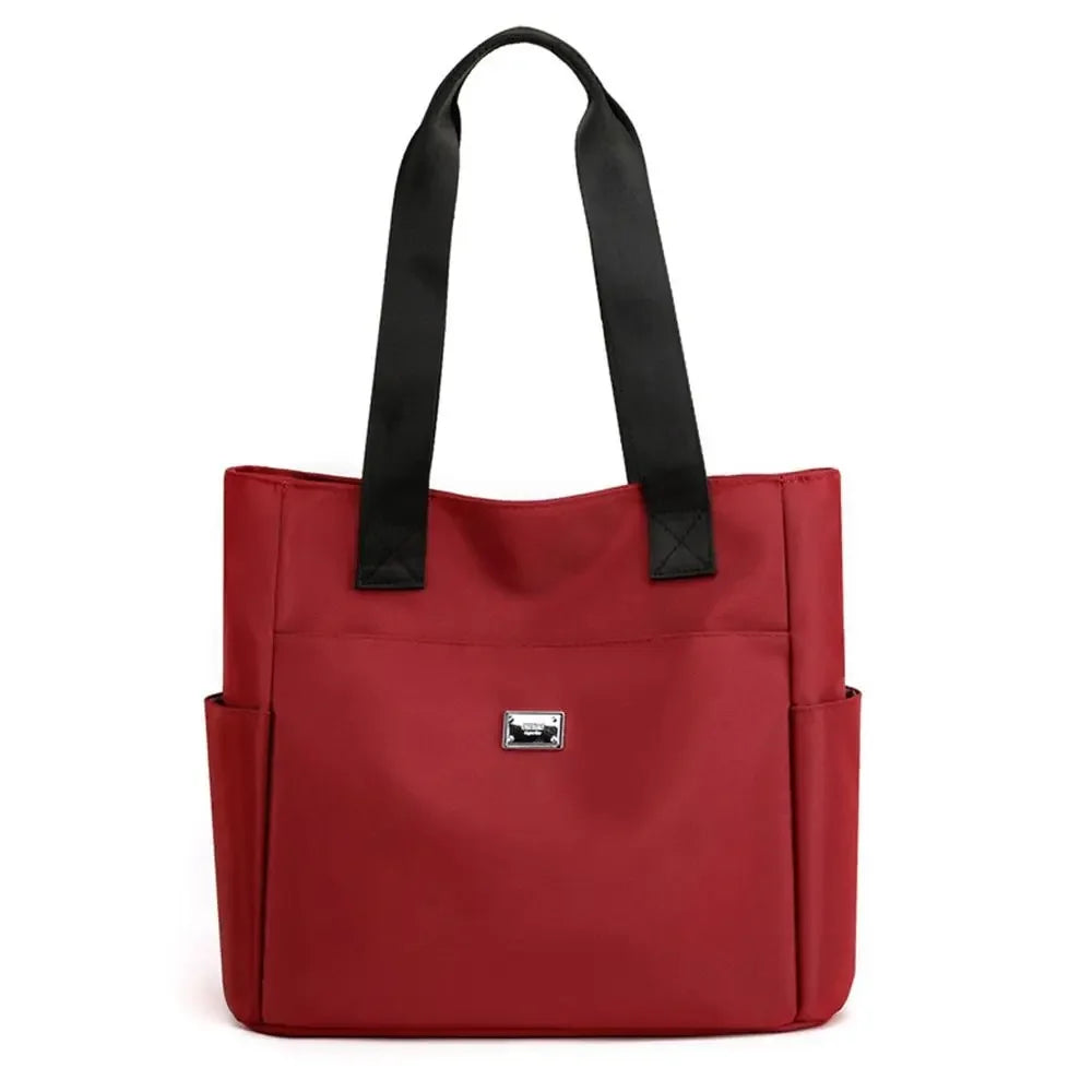A deep red nylon shoulder tote bag with black straps.