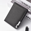 A black slim faux leather business card wallet lying on a white surface next to a book.