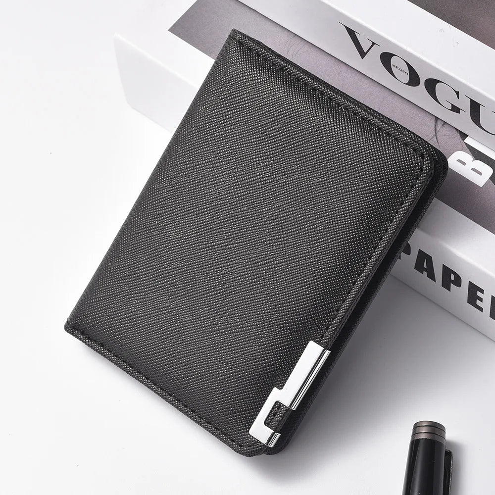 A black slim faux leather business card wallet lying on a white surface next to a book.