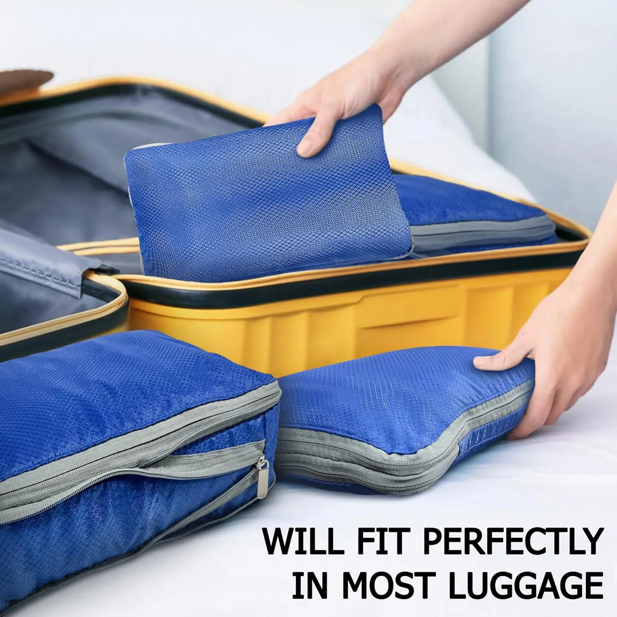 A hand places a blue compression packing cube into a yellow suitcase, demonstrating the fit of reusable packing cubes in lugg