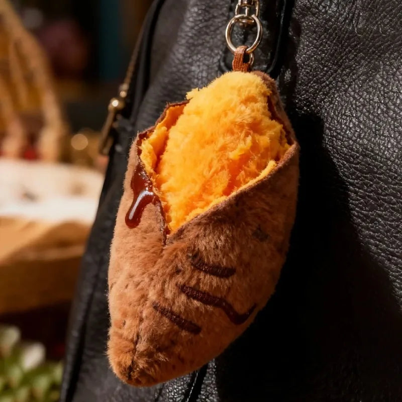 A plush keychain shaped like a roasted sweet potato with orange fluffy stuffing and a brown exterior.