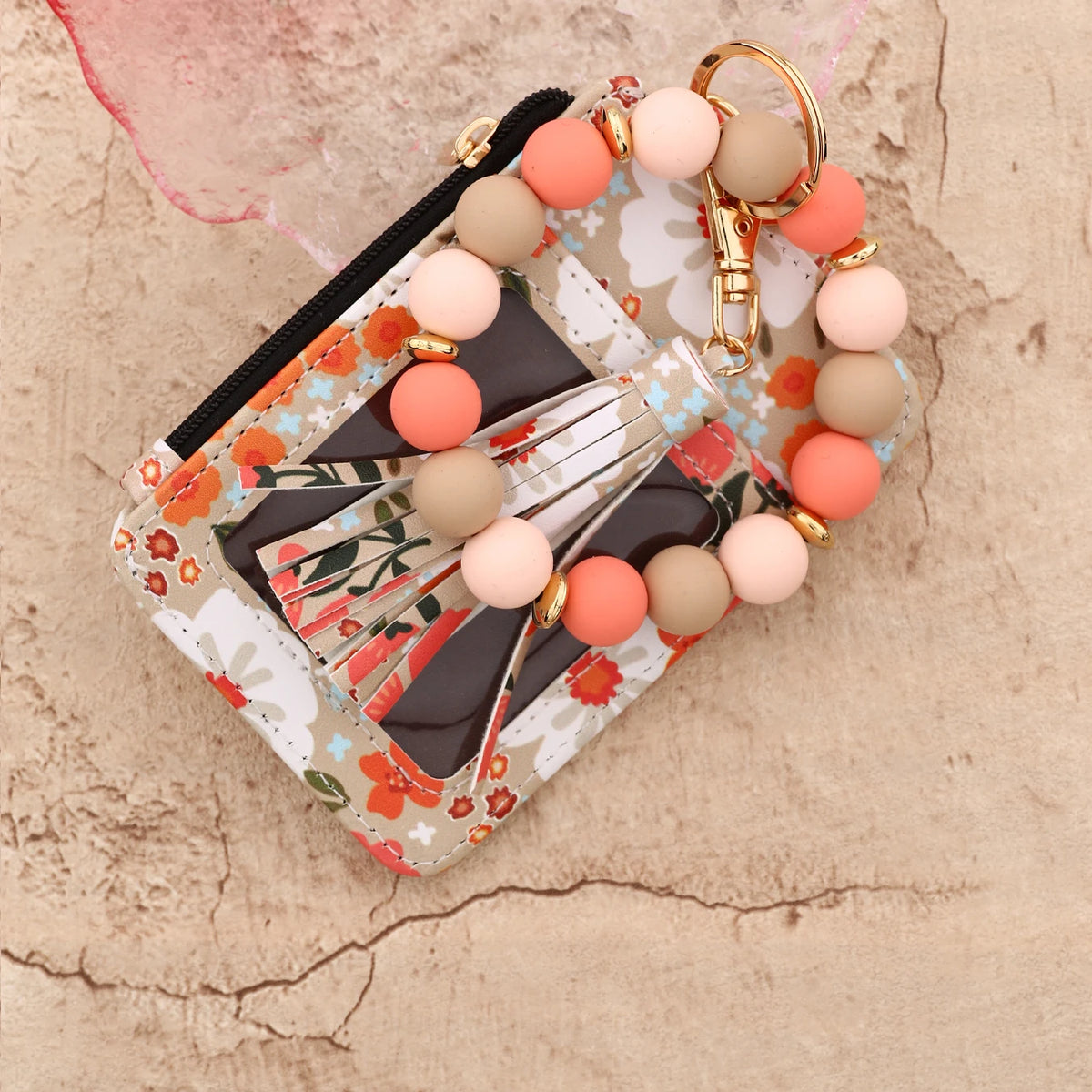 Cartera llavero de cuero PU silicona floral rosa con cadena dorada y cuentas redondas sobre fondo texturizado.