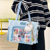 A light blue transparent shoulder tote bag featuring various ticket and photo cards with a fluffy white charm.
