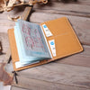 A brown genuine cowhide leather passport and ticket holder with several cards inside, resting on a wooden surface.