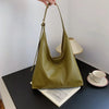 Ein hellolivgrüner Retro-Canvas-Taschenbeutel liegt auf einem dunklen Tisch neben einer weißen Tasse und Untertasse.
