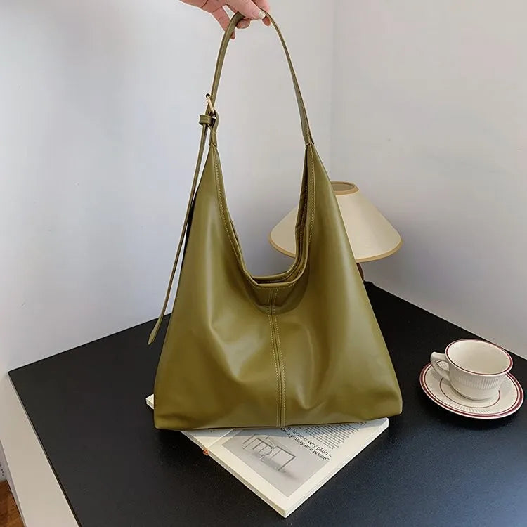 Ein hellolivgrüner Retro-Canvas-Taschenbeutel liegt auf einem dunklen Tisch neben einer weißen Tasse und Untertasse.