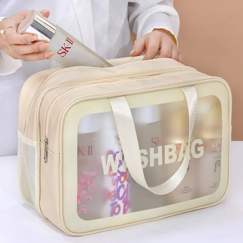 Una bolsa de cosméticos beige con ventana transparente mostrando productos de cuidado de la piel y una botella de spray, sost