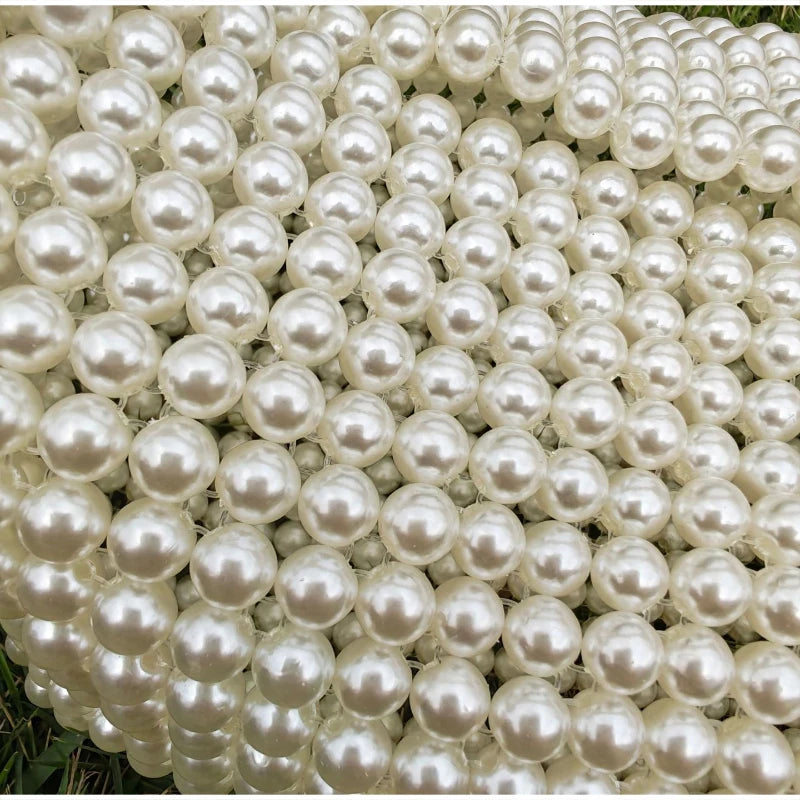 A close-up view of a clutch bag covered entirely in small, round pearls.