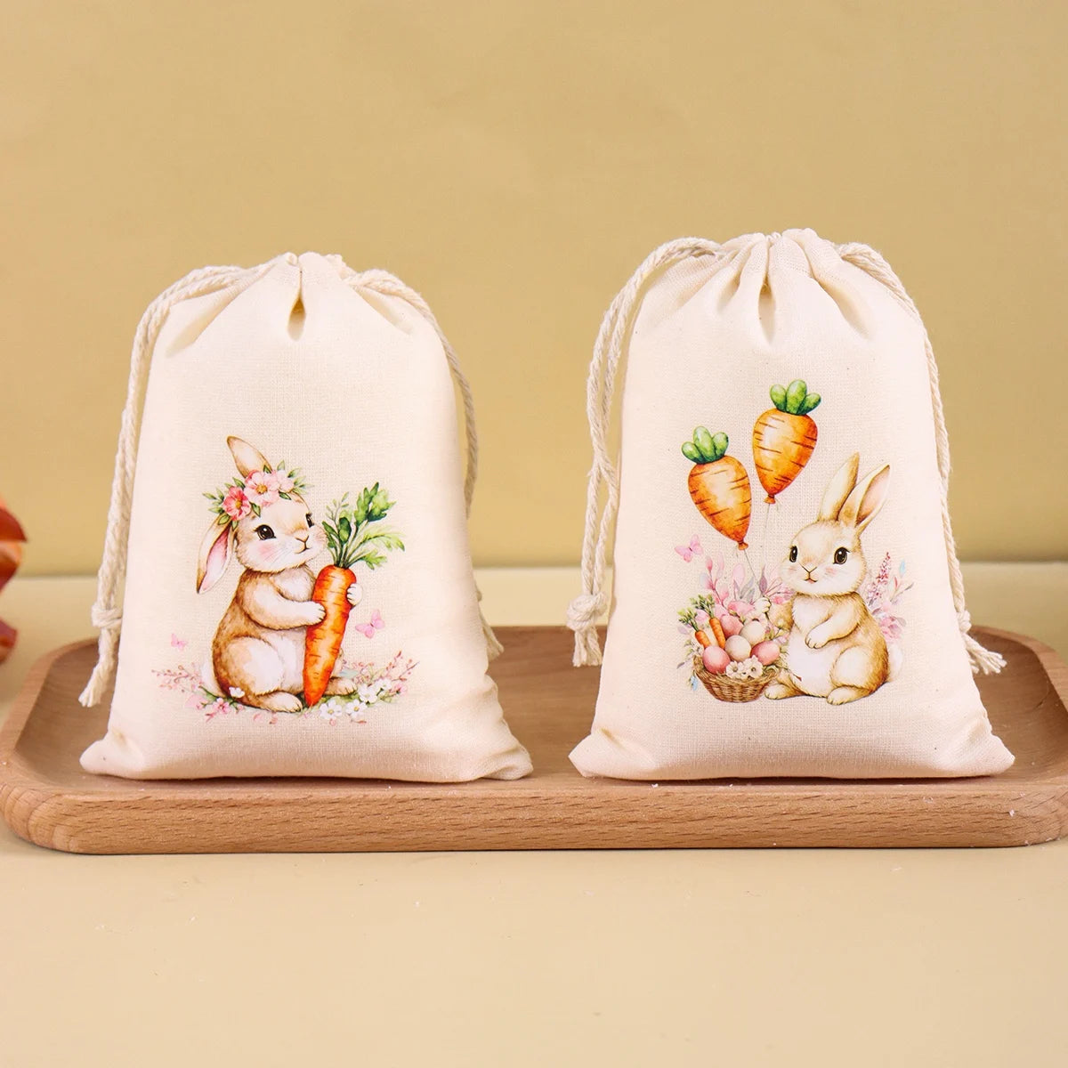 A set of six light beige drawstring gift bags featuring illustrations of Easter bunnies and carrots.