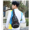 A young man wearing a white shirt and jeans is carrying a black nylon chest sling bag outdoors.