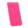 A bright pink heat-resistant silicone mat with textured ridges for styling tools.