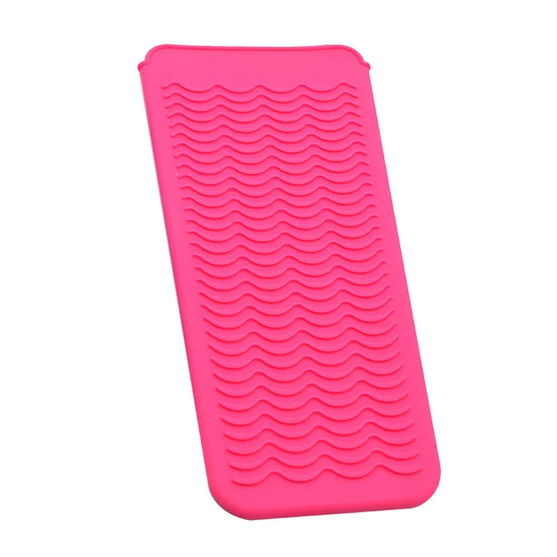 A bright pink heat-resistant silicone mat with textured ridges for styling tools.