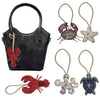 A black leather bag charm featuring a red crab and a starfish, along with several other rhinestone beaded charms.