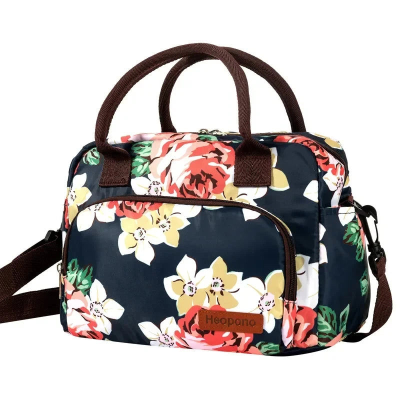 Una lonchera azul marino con estampado floral y asas marrones.